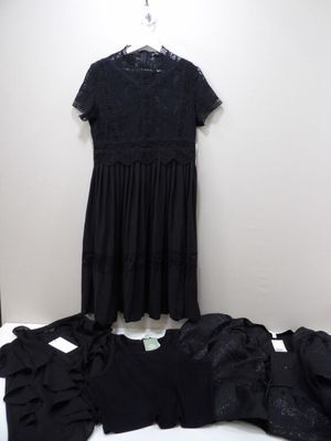 black lace dress on a hanger next to a pile of clothes