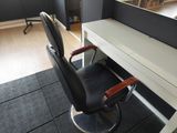 a black chair sitting in front of a desk with a mirror