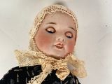 a small doll with a black dress and a yellow scarf