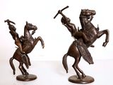 une paire de statues en bronze représentant un homme à cheval et une femme à cheval