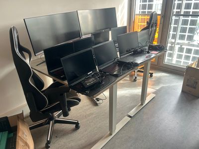 trois écrans d'ordinateur posés sur un bureau devant une fenêtre