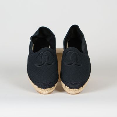 une paire d'espadrilles noires avec un logo sur la semelle