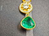 une photo d'une paire de boucles d'oreilles en émeraude et diamant posées sur un morceau de tissu