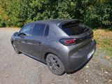 the rear end of a grey car parked on a gravel road