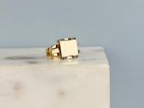 La bague en or repose sur un bloc de marbre blanc