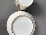 two white and gold china cups and saucers on a gray surface