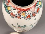 a white vase with a red and blue design next to a small white bowl