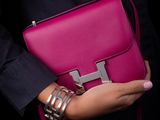 woman in a black shirt holding a pink handbag and bracelets