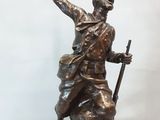 statue en bronze représentant un homme muni d'une épée et coiffé d'un chapeau, perché sur un rocher