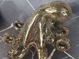 a gold octopus figurine sitting on a tile floor