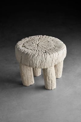 un petit tabouret en pierre posé sur une surface grise