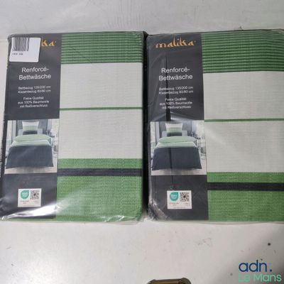 une parure de linge de lit verte et blanche posée sur une table blanche