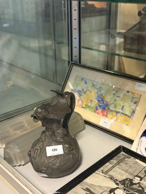 une vitrine en verre sur laquelle sont posés un vase et des photos