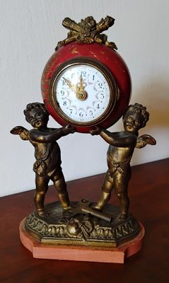 une horloge posée sur une table où se trouve une statue représentant deux enfants