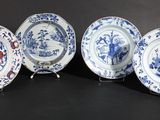 four blue and white plates with designs on them sitting on a black surface
