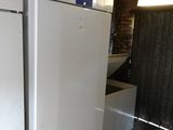 two white refrigerators in a room with a brick wall