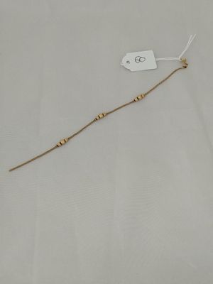 a close up of a gold beaded necklace with a tag on it