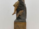 bronze statue of a man sitting on a rock with a dog