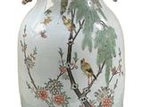 a white vase with a bird and flowers on it