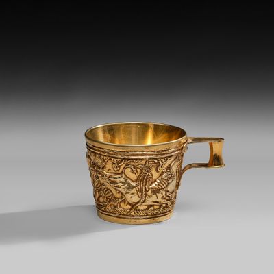a gold cup with a design of birds and flowers on it
