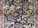 a blue and red rug with birds and flowers on it