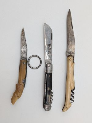 trois couteaux et un décapsuleur sur une table