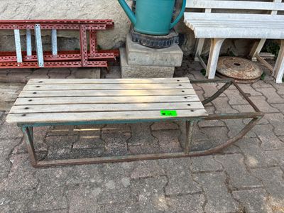 a wooden bench sitting next to a blue watering can