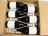 six bottles of wine in a cardboard box on a table