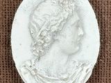 a close up of a white medallion with a woman ' s face on it