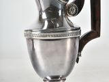 a silver pitcher sitting on a table with a wooden handle