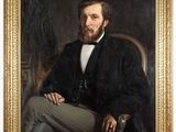 portrait of a man in a black coat and white shirt sitting in a chair