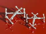 deux paires de boucles d'oreilles en argent posées sur une surface rouge