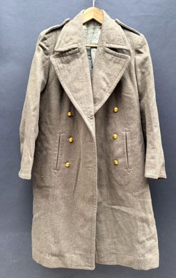 manteau en laine avec des boutons dorés, suspendu à un cintre sur fond bleu