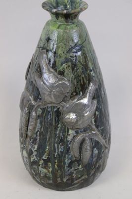 un vase vert orné d'un oiseau sur fond blanc