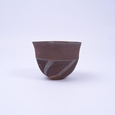 un bol marron posé sur une surface blanche