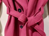 the coat is pink and has a large bow on the front