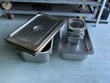 several pans of food are sitting on the floor in front of a shelf