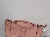 un sac à main en cuir rose posé sur une surface en marbre, près d'un mur blanc