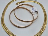 un gros plan d'un collier et d'un bracelet en or posés sur une surface blanche