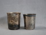 pair of antique silverplated shot glasses on a grey background