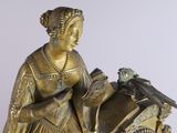 a gold clock with a lady holding a bird on top of it