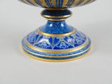 a blue and gold bowl on a stand on a table