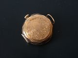 a small gold pocket watch on a black surface