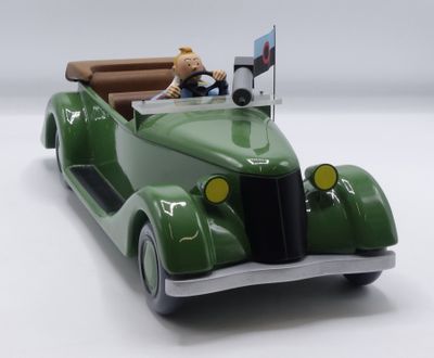 une petite voiture verte avec un ours en peluche sur la banquette arrière