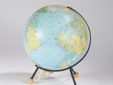un globe bleu et jaune posé sur un socle en bois