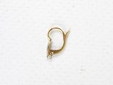 a close up of a small gold earring on a white surface
