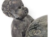 a statue of a baby holding a ball on a white surface