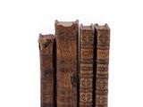 several old books stacked on top of each other on a white surface