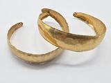a pair of gold plated cuff bracelets with curved ends