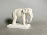 statue of an elephant on a white base against a gray background